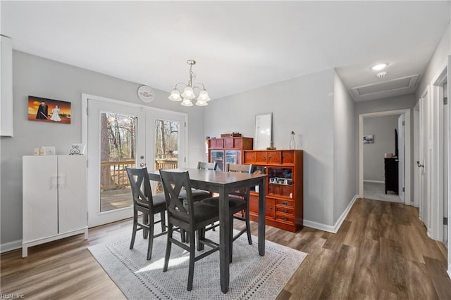 dining space featuring french doors, dark hardwood / wood-style floors, and a chandelier