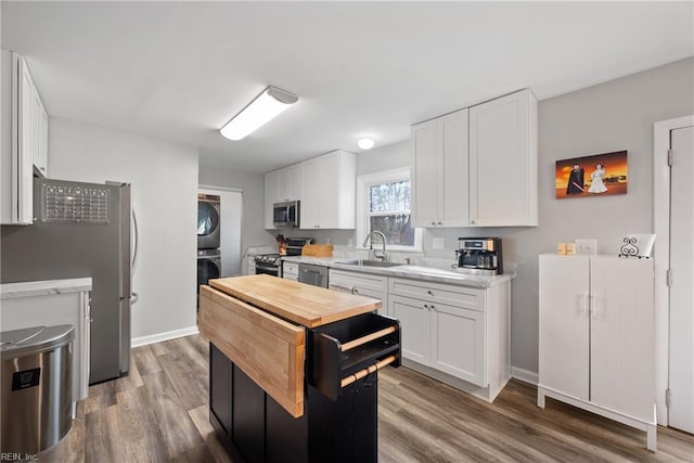 kitchen with sink, white cabinetry, stainless steel appliances, dark hardwood / wood-style floors, and stacked washer / dryer