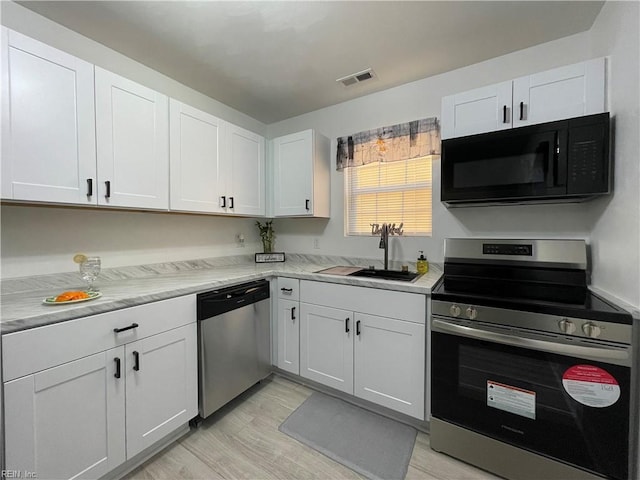 kitchen with white cabinetry, stainless steel appliances, sink, and light wood-type flooring