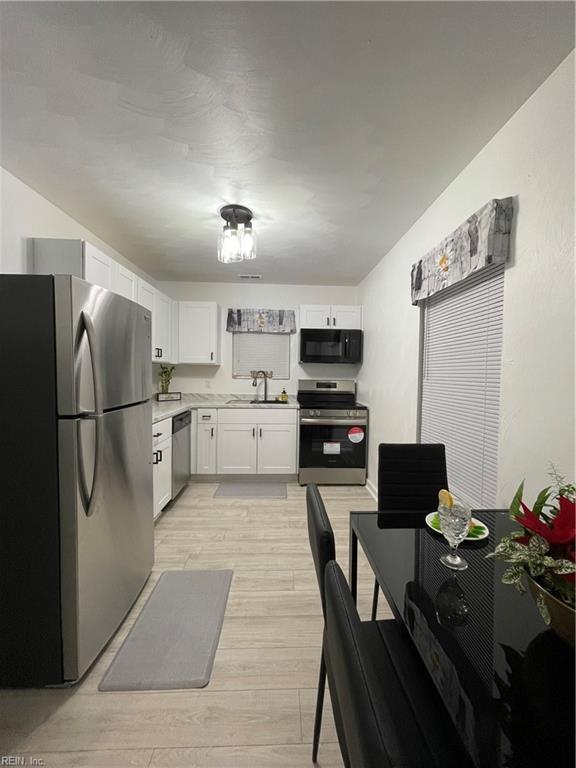 kitchen featuring stainless steel appliances, sink, white cabinets, and light wood-type flooring