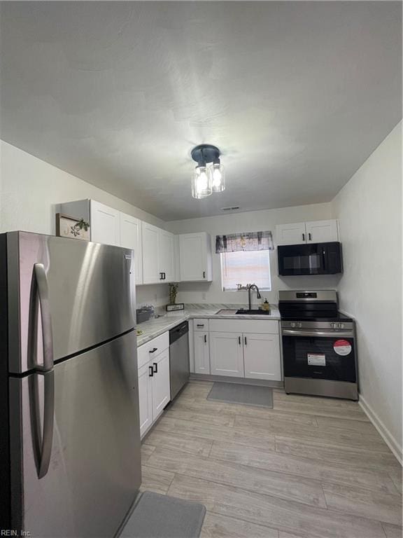 kitchen featuring white cabinetry, stainless steel appliances, sink, and light wood-type flooring