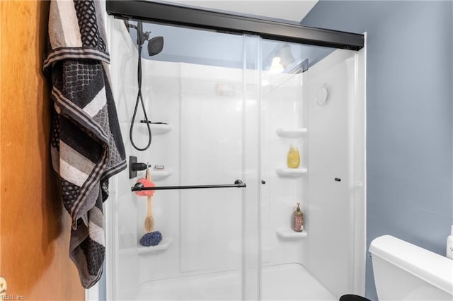 bathroom featuring a shower with door and toilet