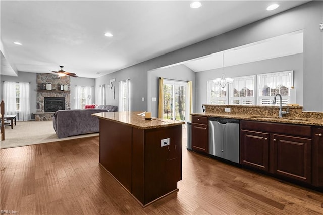 kitchen featuring pendant lighting, sink, dishwasher, dark brown cabinetry, and light stone countertops