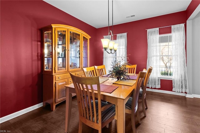 dining area featuring dark hardwood / wood-style flooring and an inviting chandelier