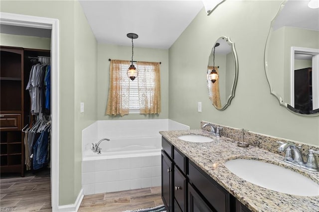 bathroom with vanity and tiled tub