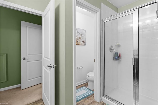 bathroom featuring wood-type flooring, an enclosed shower, and toilet