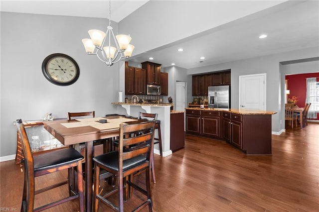 dining area with lofted ceiling, dark hardwood / wood-style floors, and a chandelier