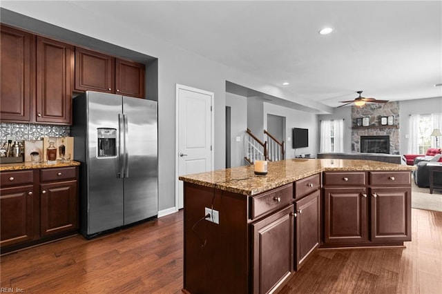 kitchen with a kitchen island, a fireplace, tasteful backsplash, dark hardwood / wood-style flooring, and stainless steel fridge with ice dispenser