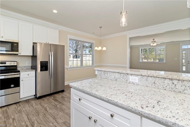 kitchen featuring crown molding, appliances with stainless steel finishes, pendant lighting, and white cabinets