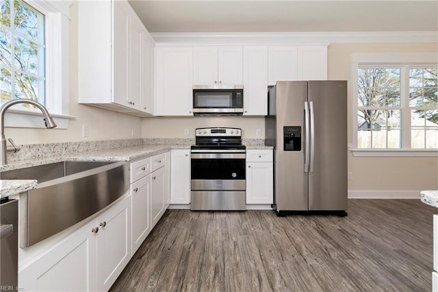 kitchen with light stone counters, appliances with stainless steel finishes, sink, and white cabinets