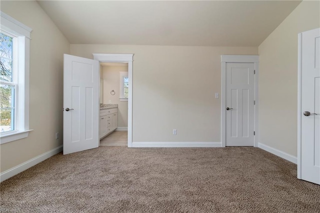 unfurnished bedroom with connected bathroom and light carpet