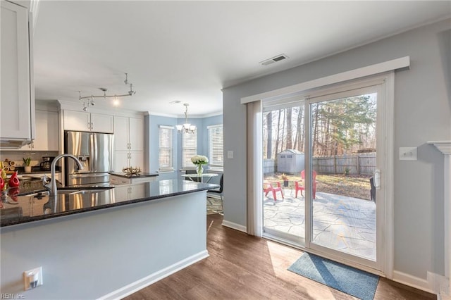 kitchen featuring pendant lighting, white cabinetry, dark stone counters, and stainless steel refrigerator with ice dispenser