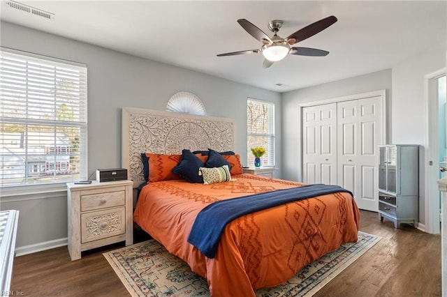 bedroom featuring multiple windows, dark hardwood / wood-style flooring, a closet, and ceiling fan