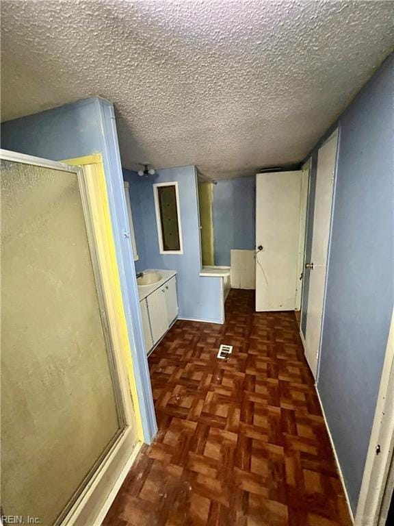 bathroom featuring parquet floors, a shower with shower door, and a textured ceiling