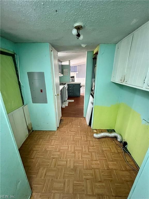 interior space featuring light parquet flooring, electric panel, and a textured ceiling