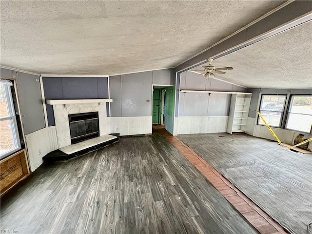 unfurnished living room with a high end fireplace, dark wood-type flooring, a textured ceiling, and vaulted ceiling