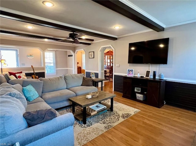 living room featuring crown molding, beam ceiling, light hardwood / wood-style flooring, and ceiling fan