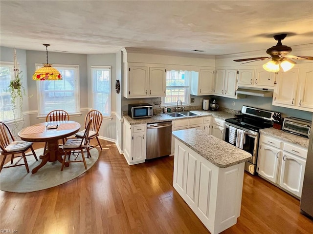 kitchen with dark wood-type flooring, sink, decorative light fixtures, a kitchen island, and stainless steel appliances