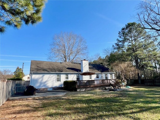 rear view of property featuring a wooden deck, a patio area, and a lawn