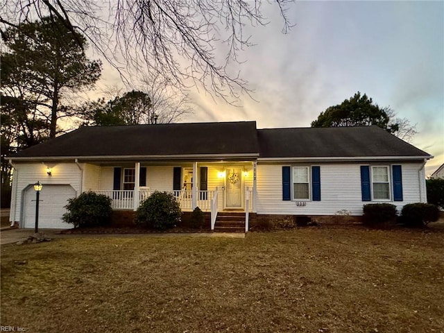 single story home featuring a porch, a garage, and a yard