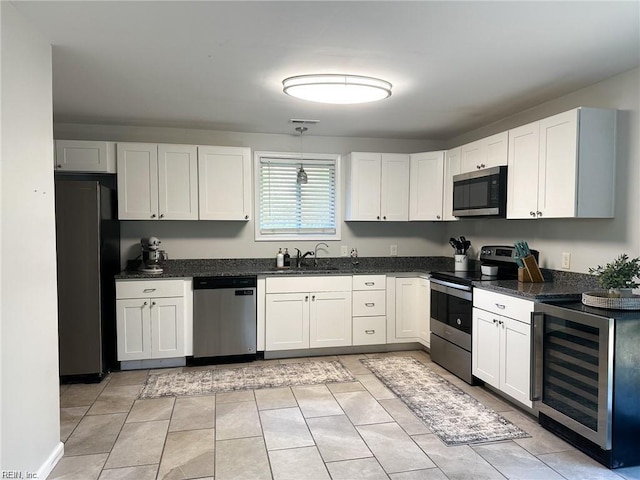 kitchen with stainless steel appliances, beverage cooler, sink, and white cabinets