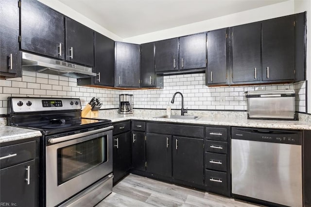 kitchen featuring tasteful backsplash, sink, stainless steel appliances, and light hardwood / wood-style floors