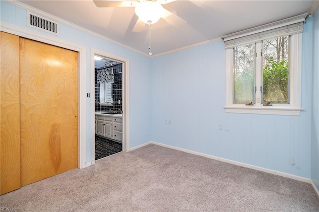 unfurnished bedroom featuring ornamental molding, carpet, connected bathroom, and ceiling fan