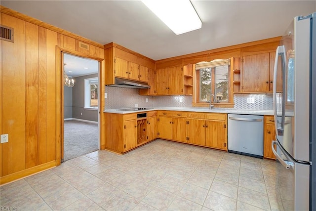 kitchen featuring tasteful backsplash, sink, wooden walls, and appliances with stainless steel finishes