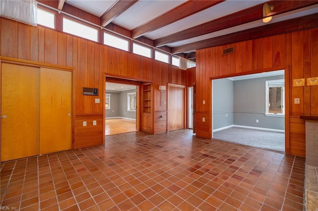 unfurnished living room featuring wooden walls and beamed ceiling