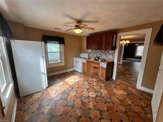 kitchen with ceiling fan with notable chandelier, white appliances, sink, and backsplash