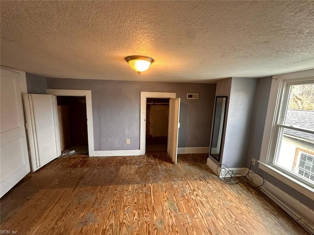 unfurnished bedroom featuring hardwood / wood-style floors, a textured ceiling, and a closet