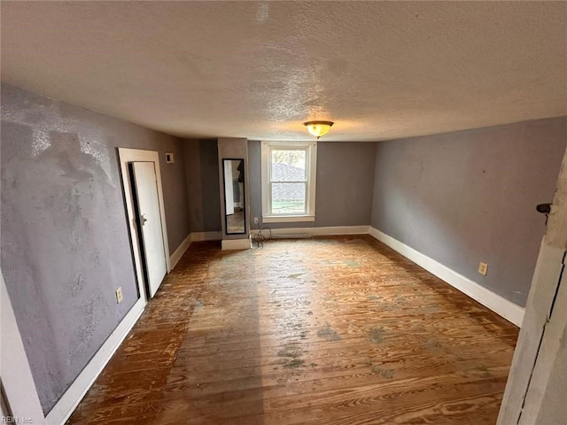 empty room with wood-type flooring and a textured ceiling