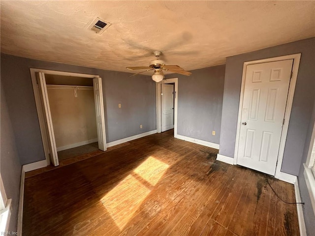 unfurnished bedroom with dark wood-type flooring, a textured ceiling, ceiling fan, and a closet