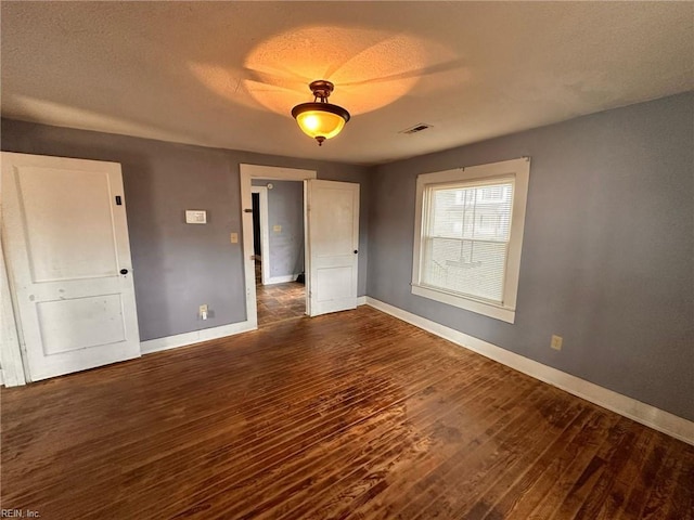 unfurnished bedroom with dark hardwood / wood-style floors and a textured ceiling