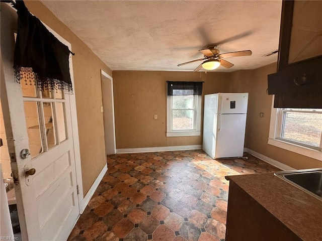 kitchen with white fridge, sink, a textured ceiling, and ceiling fan