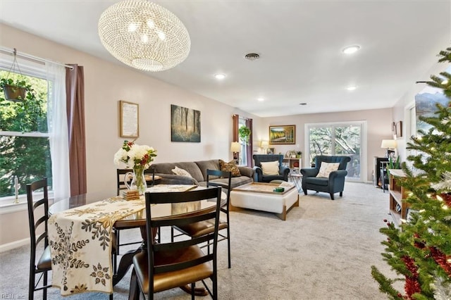 dining room featuring an inviting chandelier, light colored carpet, and a wealth of natural light