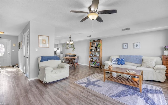 living room featuring hardwood / wood-style floors, ceiling fan with notable chandelier, and a textured ceiling