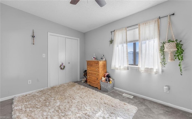 carpeted bedroom featuring ceiling fan, a closet, and a textured ceiling