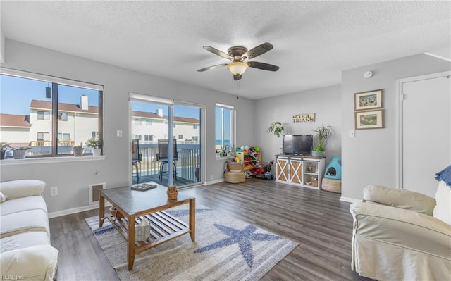 living room featuring ceiling fan, dark hardwood / wood-style floors, and a textured ceiling