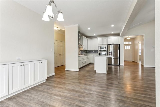 kitchen with a kitchen island, appliances with stainless steel finishes, decorative light fixtures, white cabinets, and decorative backsplash