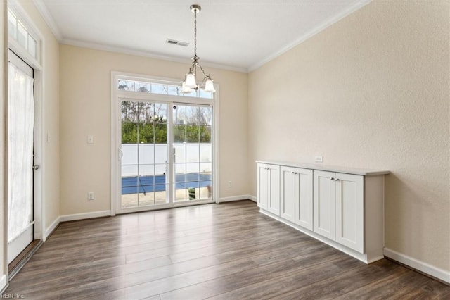 unfurnished dining area featuring crown molding, dark hardwood / wood-style floors, and an inviting chandelier