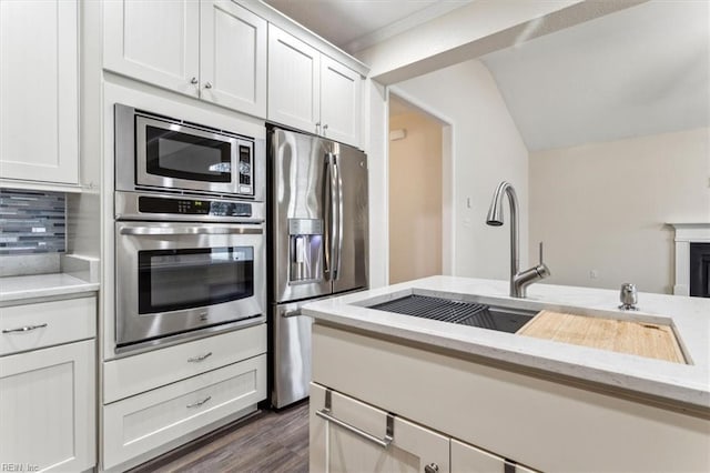 kitchen featuring stainless steel appliances, white cabinetry, light stone countertops, and sink