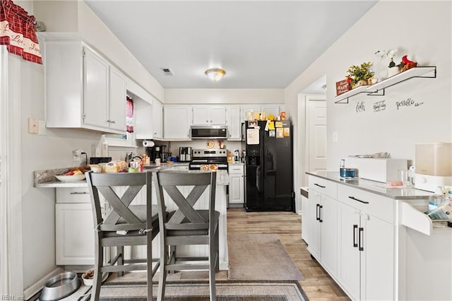 kitchen featuring appliances with stainless steel finishes, light wood-type flooring, and white cabinets