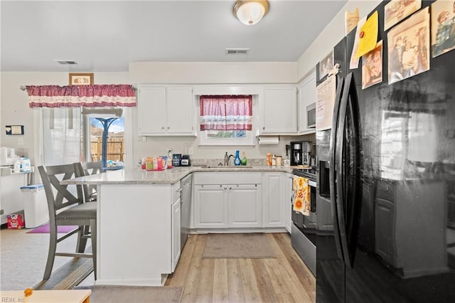 kitchen with white cabinetry, a kitchen breakfast bar, stainless steel appliances, and kitchen peninsula