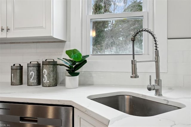 details with sink, dishwasher, white cabinetry, light stone counters, and decorative backsplash