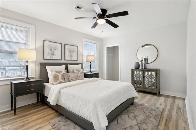 bedroom featuring multiple windows, ceiling fan, and light wood-type flooring