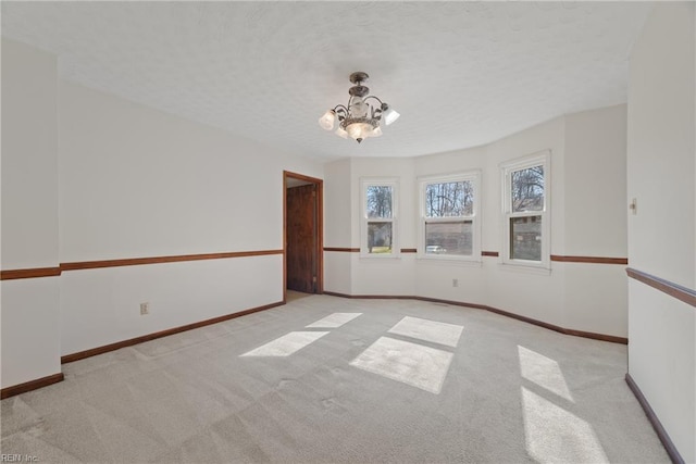 carpeted empty room with a chandelier and a textured ceiling