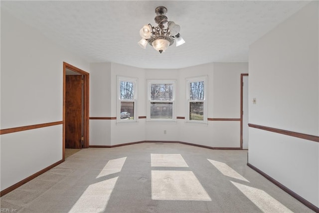 unfurnished room with light carpet, a notable chandelier, and a textured ceiling