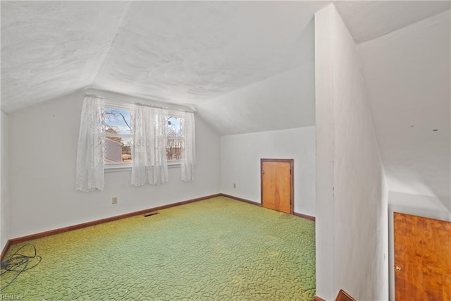 additional living space with carpet floors, vaulted ceiling, and a textured ceiling