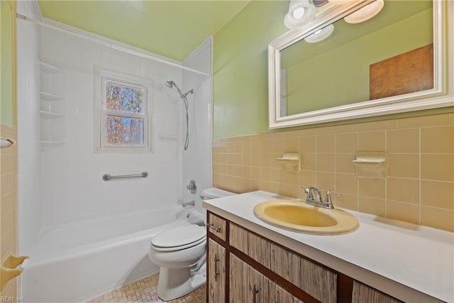 full bathroom featuring tiled shower / bath, tile walls, vanity, and toilet